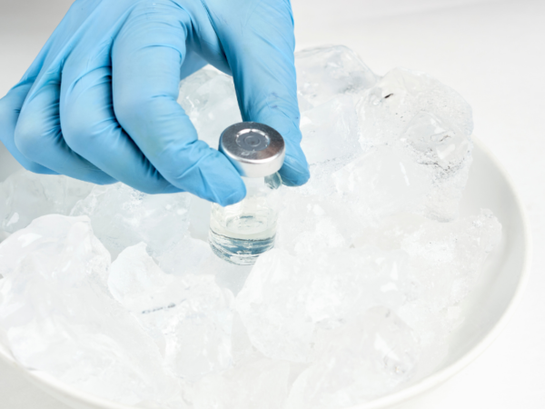 Close-up of a doctor’s hand reaching into a container of ice to remove a vial of temperature-sensitive medication